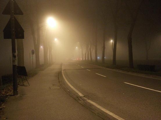 A foggy road in Ferrara, Italy. Lights are smooth, colours are strange and fading, everything is silent.